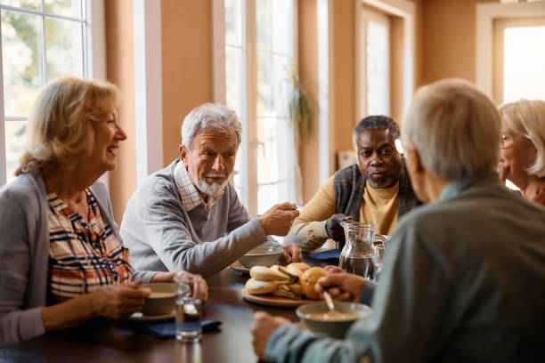 istock Senior man talking to his friends while eating at dining table at nursing home. 1467102762