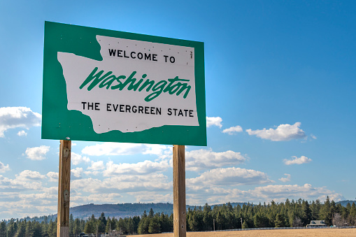 A roadside welcome to Washington the Evergreen State sign in the rural  area near Spokane, Washington, USA, coming from the state of Idaho.