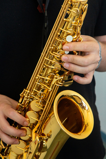 A person playing the saxophone. Close-up. We see the saxophone and the fingers.