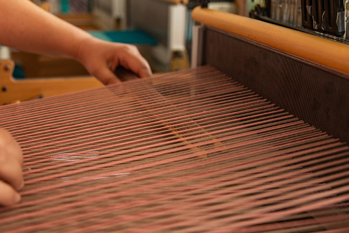 Close-up of human weaving yarn. Weaving is done by hand with traditional methods. The artist is working. Faculty of fine arts.