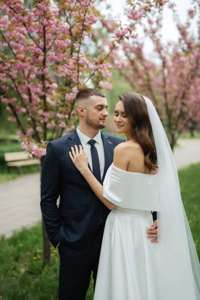 istock newlyweds walk in the park among cherry blossoms 1467110816