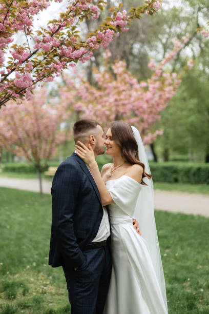 istock newlyweds walk in the park among cherry blossoms 1467111120