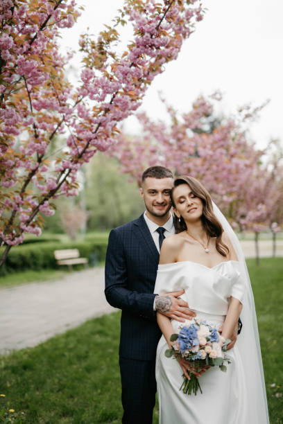 istock newlyweds walk in the park among cherry blossoms 1467112057
