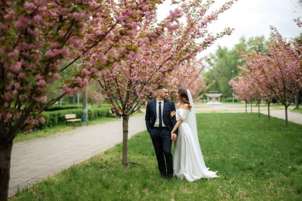 istock newlyweds walk in the park among cherry blossoms 1467112286