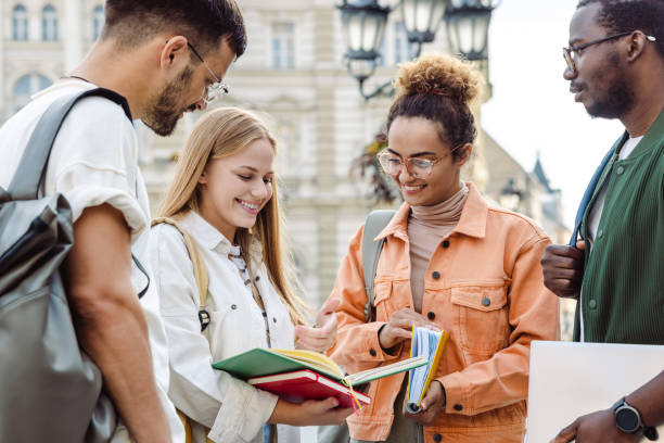 Group of University students hanging out after class A Group of University students cheerfully talking and discussing school project exchange student stock pictures, royalty-free photos & images