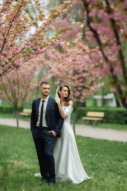 istock newlyweds walk in the park among cherry blossoms 1467113739