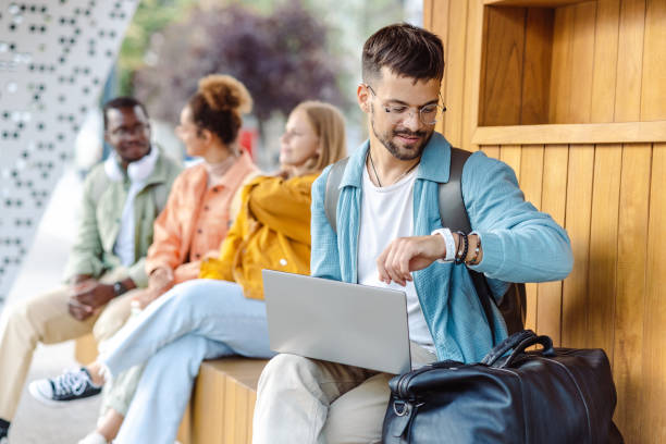 istock Male student using laptop on the bench on the bus stop 1467114532