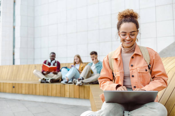 istock Young female student using laptop on the bench on campus 1467116249