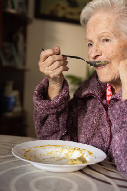 istock elderly woman eating a vegetable puree with a spoon 1467116563