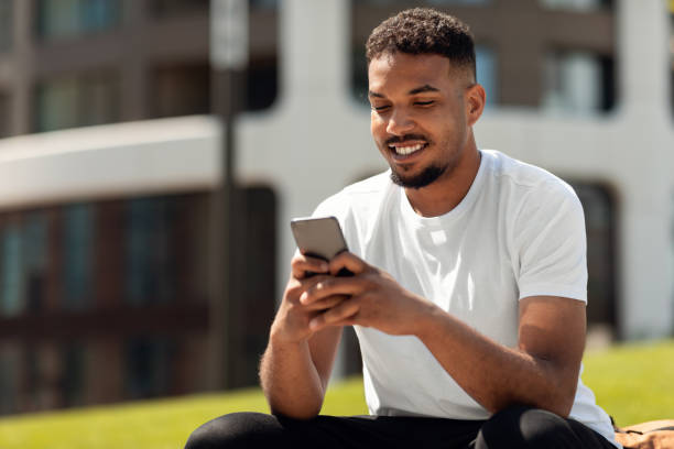 istock Handsome african american guy using smartphone outdoors while walking in urban city park, free space 1467118891