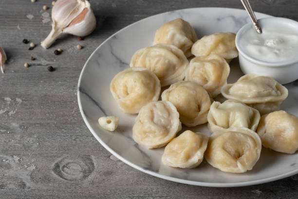 Traditional russian pelmeni, ravioli, dumplings with meat on a wooden table Traditional russian pelmeni, ravioli, dumplings with meat on a wooden table. russian pelmeni stock pictures, royalty-free photos & images