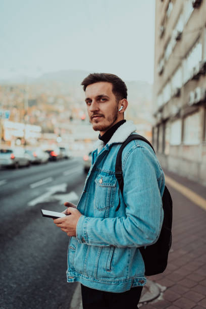 istock A student with a backpack using a smartphone on the street, checking email, writing messages and listening to music on headphones. 1467120154