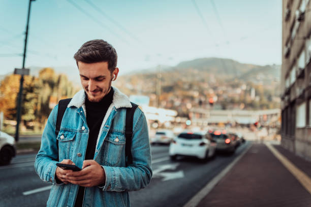 istock A student with a backpack using a smartphone on the street, checking email, writing messages and listening to music on headphones. 1467120308