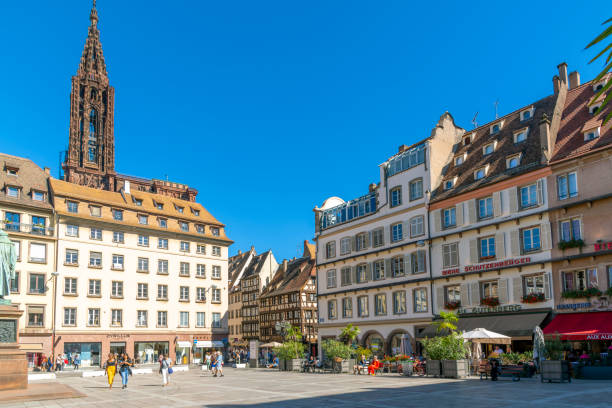 lojas e cafés alinham-se na place gutenberg ou na praça gutenberg, no centro histórico da cidade velha medieval de estrasburgo, frança, com a catedral de estrasburgo em vista. - strasbourg cathedral - fotografias e filmes do acervo