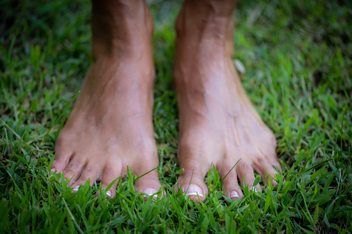 Practicing grounding, barefoot female feet touching the ground.