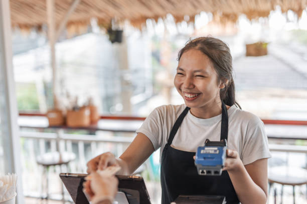 A young woman pays with a card in a restaurant stock photo