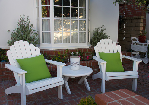 Pair of Adirondack chairs with green pillows on the patio
