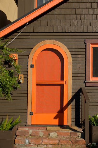 кор�ичневый коттедж с ярко-оранжевой входной дверью - screen door door porch house стоковые фото и изображения