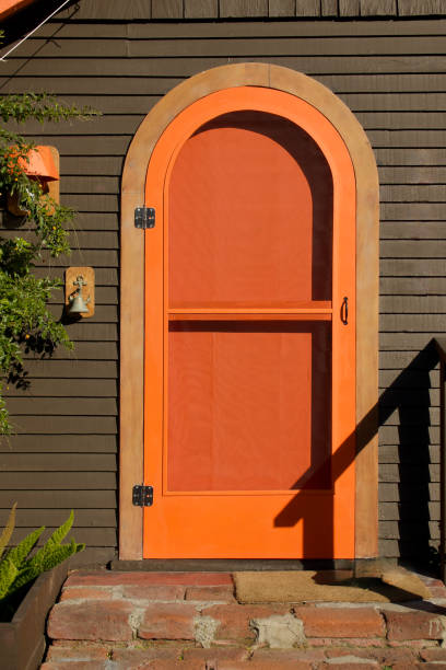 cottage marrone con una porta d'ingresso arancione brillante - screen door door porch house foto e immagini stock
