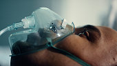 Patient face breathing oxygen mask closeup. Infected man wear respirator in ward