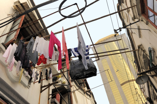 Hutong in Shanghai with just cleaned clothes hanging outside. At background very high office building.