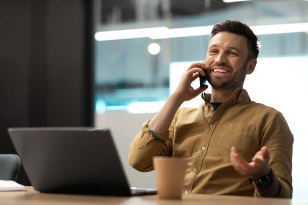 istock Happy Businessman Talking On Mobile Phone Using Laptop In Office 1467141025