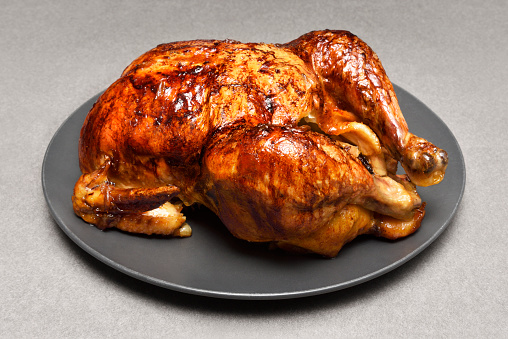 Juicy roasted whole chicken on a black plate