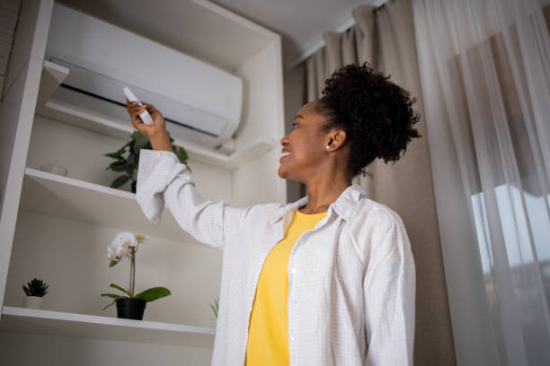 istock Young woman turning on air conditioner 1467150236