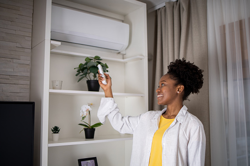 Woman turning on air conditioner with remote