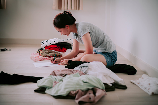 Woman taking her clothes to sell and is calculating the money that will be received from the sale