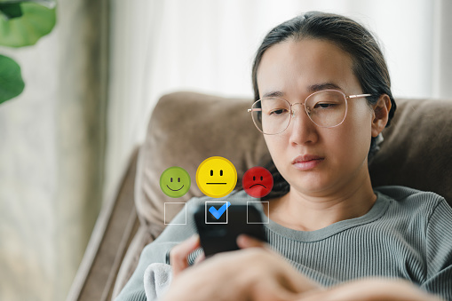 Customer service evaluation concept. Customers feel indifferent, give mediocre scores, woman using smartphone pressing face emoticon Satisfaction Rating indifferent in satisfaction, product, service