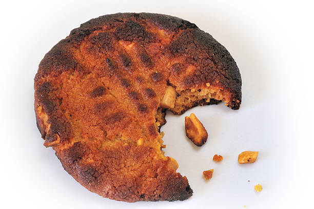 Burned biscuit A burned, half-eaten biscuit, with a few crumbs, on a white background. awful taste stock pictures, royalty-free photos & images