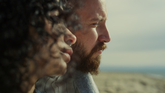 Couple face looking calm on relax sea beach. Close up mixed race people close eyes on nature. Portrait of dreamy lovers enjoy vacation. Two romantic partners rest together on sunny day. Natural beauty