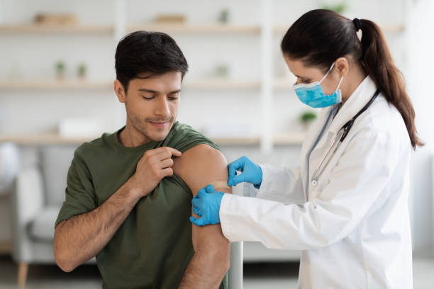 Young soldier getting vaccinated against coronavirus at clinic stock photo