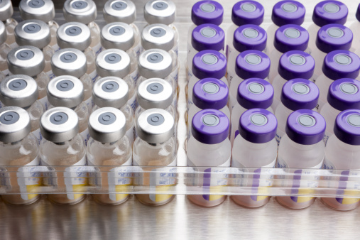 Vials of medicine that are injected by hypodermic syringe on a stainless steel background