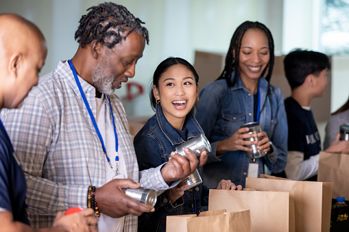 Diverse group of volunteers package groceries for community at food bank