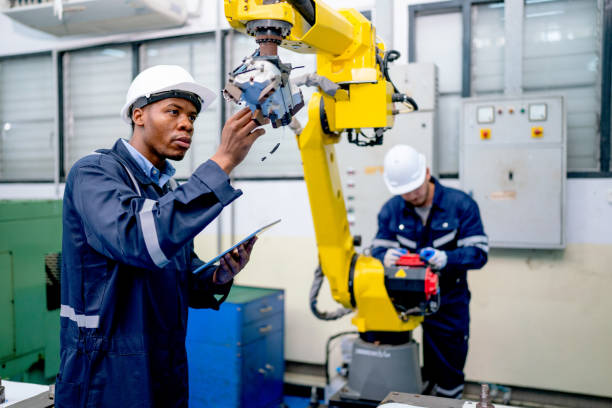 istock African American engineer or technician worker hold part of robotic arm and check  the function of machine and co-worker support in the back in factory workplace. 1467185953