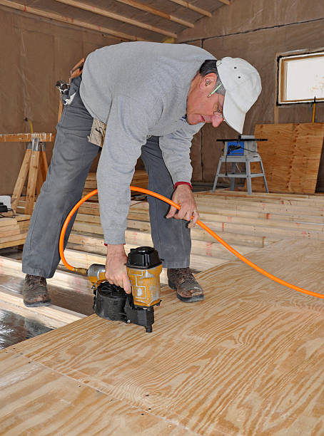 Man nailing plywood floor with nail gun stock photo