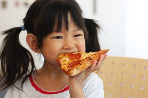 little girl eats a slice of pizza, four years old