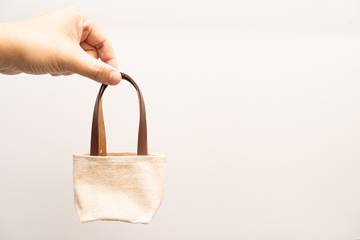 small full canvas bag with ties, Reusable eco bag. Empty small cotton bag with string on white background.