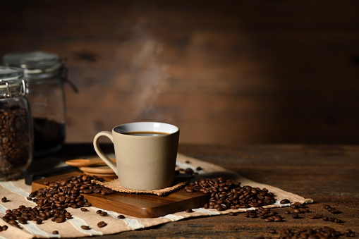 istock Cup of coffee with smoke and coffee beans on old wooden background 1467199054