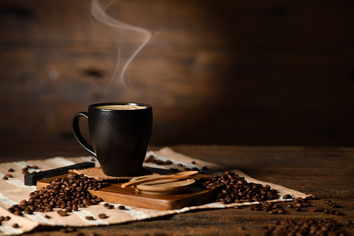 Taza de café con humo y granos de café sobre fondo de madera viejo photo