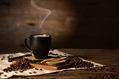 istock Cup of coffee with smoke and coffee beans on old wooden background 1467199060