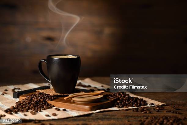 Cup Of Coffee With Smoke And Coffee Beans On Old Wooden Background Stock Photo - Download Image Now