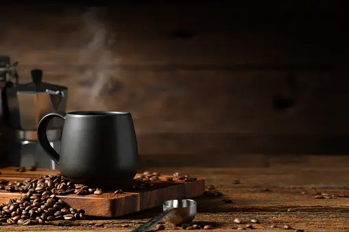 https://media.istockphoto.com/id/1467199121/photo/cup-of-coffee-with-smoke-and-coffee-beans-on-old-wooden-background-moka-pot-and-coffee-cup.webp?b=1&s=170667a&w=0&k=20&c=hAR5FuEZPY7dGwxrgdsVEOQpxLfwhrbxkIG0j4cYRwA=