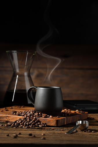 istock Cup of drip coffee with smoke and coffee beans on old wooden background 1467199130