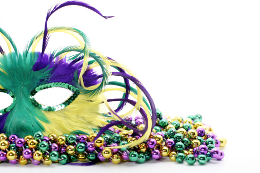 Feathered Mardi Gras mask laying on colorful beads