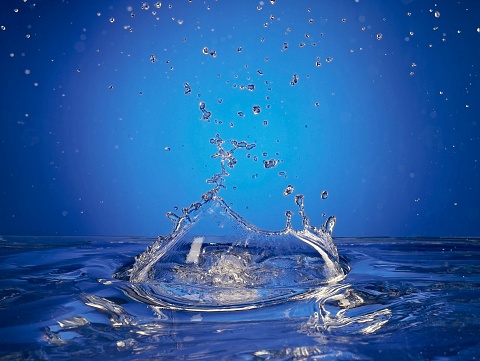 Close up of splashing water droplet. Blue Background