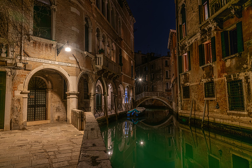 Illuminated lights by gondolas moored at Grand Canal with beautiful view of Church of San Giorgio Maggiore against blue sky at dusk in Venice,Italy