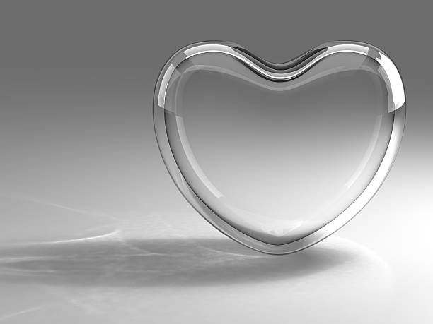 A transparent glass heart is balanced on its edge  stock photo